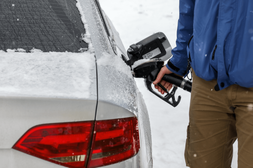 man pumping gas into a snowy car